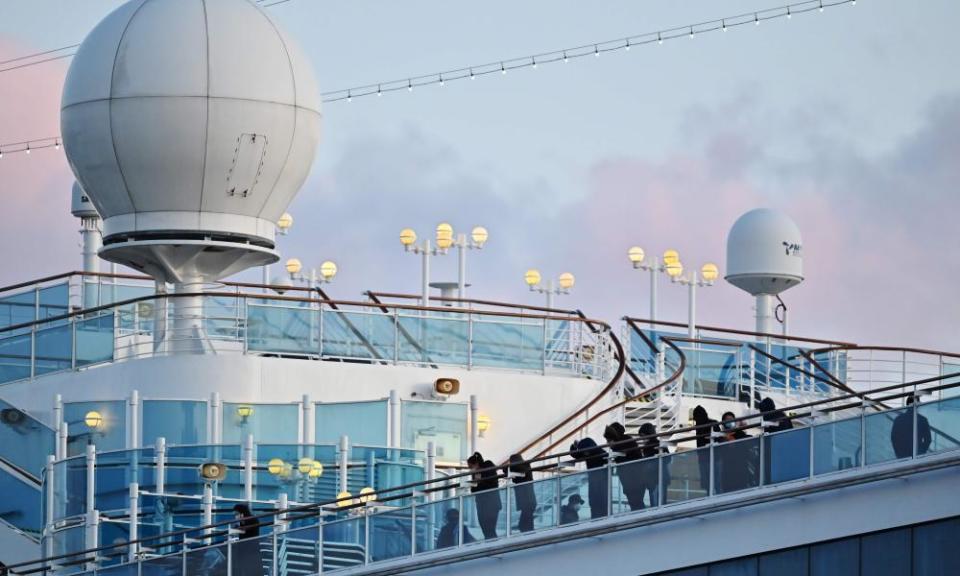 Some of the remaining quarantined passengers look out from the deck of the Diamond Princess