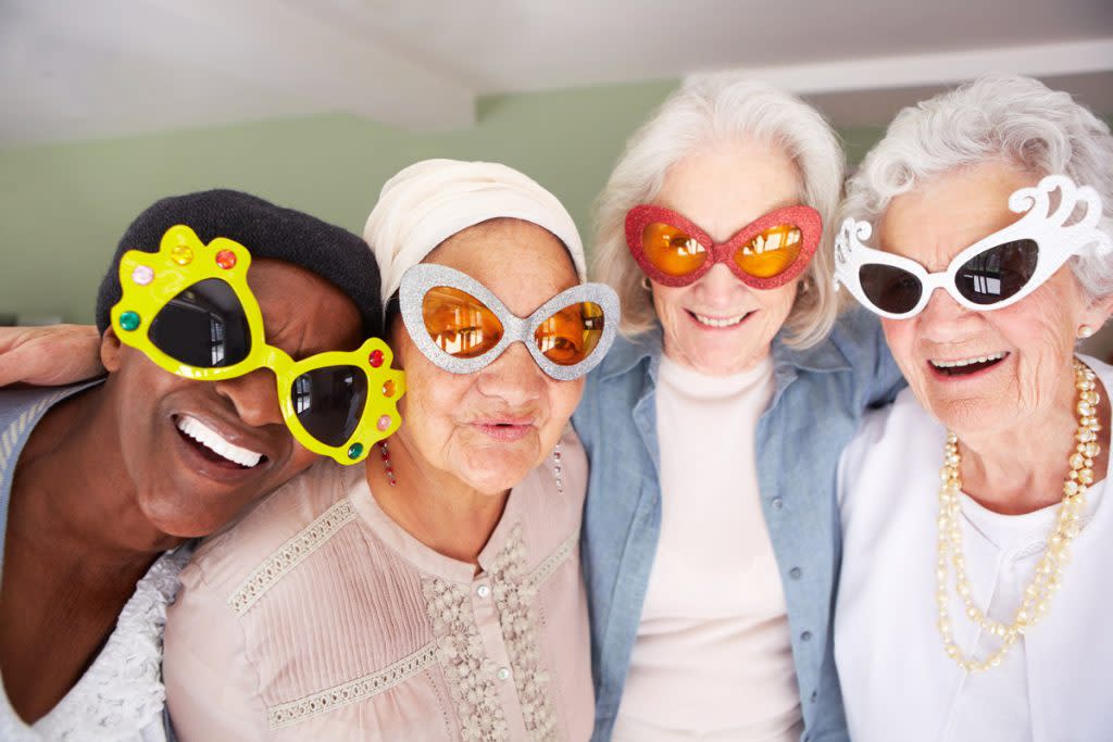 A group of women who are all senior citizens smile at the camera. This photo represents who pays for social security: you.