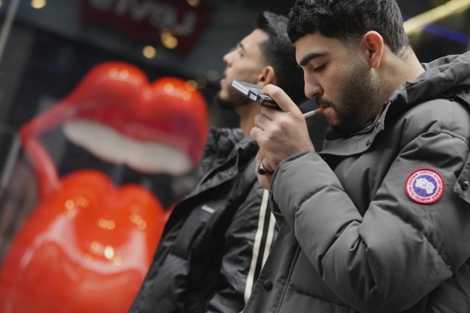 A man smokes on a street, in London, Tuesday, April 16, 2024. A bold plan to ban anyone born after 2008 from ever legally buying cigarettes in Britain faces its first test in Parliament. The bold plan has divided the governing Conservatives, with some hailing its public health benefits and others condemning it as state overreach. (AP Photo/Kin Cheung)