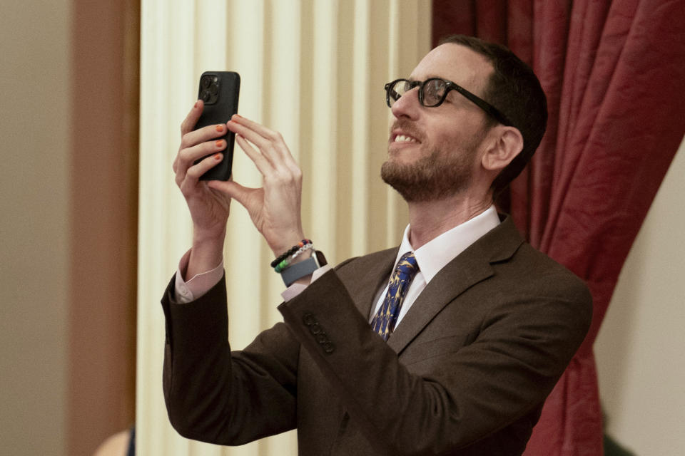 State Sen. Scott Wiener, D-San Francisco, takes a photo of the voting as his climate bill was approved by the Senate at the Capitol in Sacramento, Calif., Tuesday, Sept. 12, 2023. The measure, SB253, requires big companies to disclose a sweeping range of greenhouse gas emissions. Lawmakers are voting on hundreds of bills before the legislative session concludes for the year on Thursday. (AP Photo/Rich Pedroncelli)