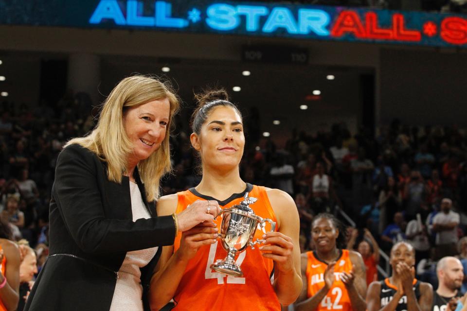 Cathy Engelbert helps Kelsey Plum lift her 2022 WNBA All-Star Game MVP trophy.