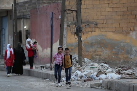 People walk past rubble in the border town of Tal Abyad