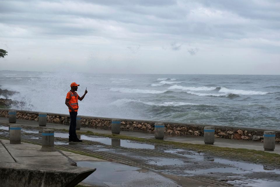 A man takes photos with his phone as the waves caused by Tropical Storm Franklin break on the sea wall in Santo Domingo, Dominican Republic, on Tuesday.