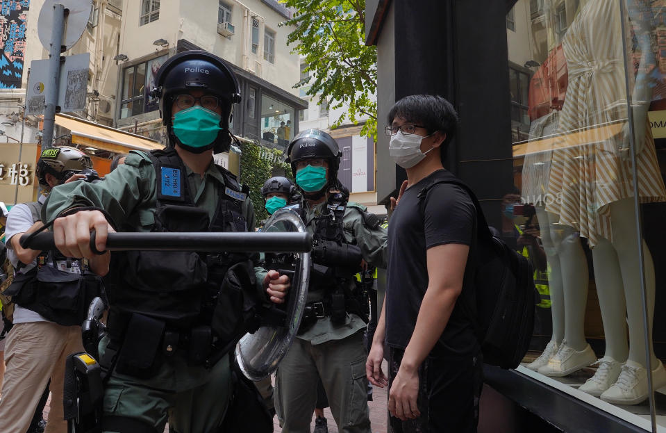 Riot police form a line as they check pedestrians gathered in the Central district of Hong Kong, Wednesday, May 27, 2020. Hong Kong police massed outside the legislature complex Wednesday, ahead of debate on a bill that would criminalize abuse of the Chinese national anthem in the semi-autonomous city. (AP Photo/Vincent Yu)