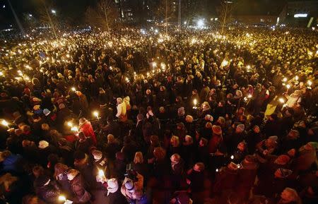 People hold candles during a memorial service held for those killed on Saturday by a 22-year-old gunman, in Copenhagen February 16, 2015. REUTERS/Hannibal Hanschke