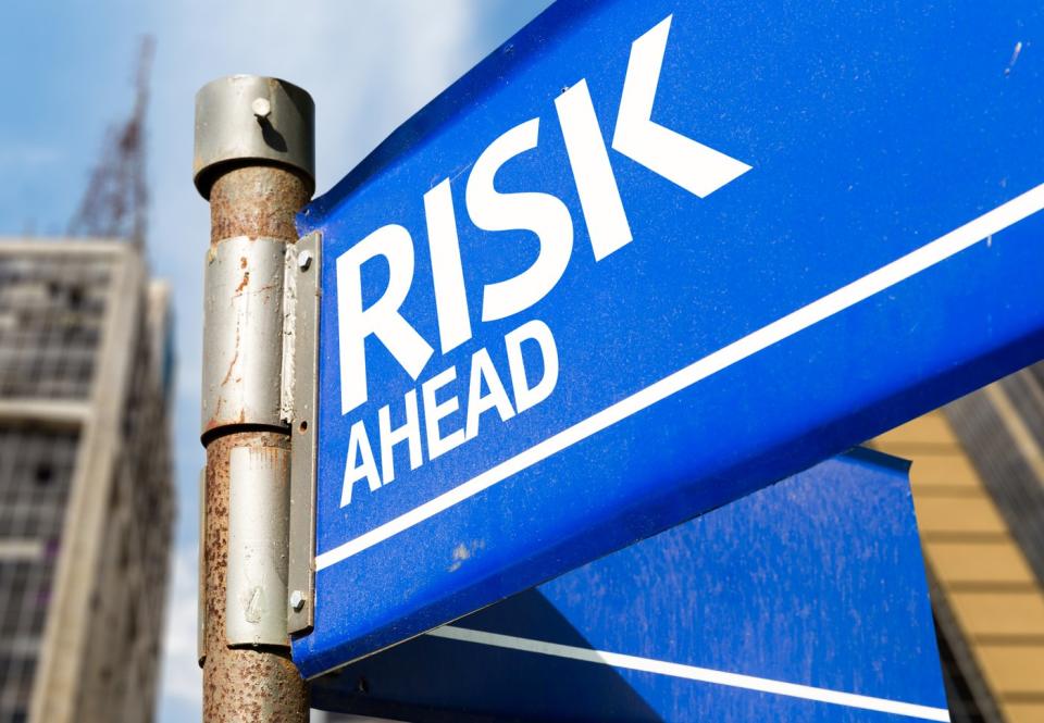 A blue street sign with the text Risk Ahead.