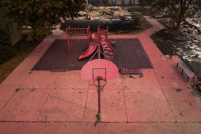 Red fire retardant blankets basketball post and a playground in the aftermath of the Almeda fire in Talent, Oregon
