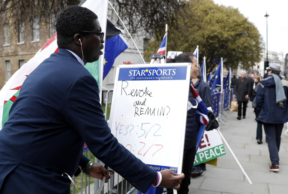 A bookmaker puts up a small white board showing the latest odds on Brexit near the media compound outside the Houses of Parliament in London, Tuesday, March 26, 2019. British Prime Minister Theresa May's government says Parliament's decision to take control of the stalled process of leaving the European Union underscores the need for lawmakers to approve her twice-defeated deal. (AP Photo/Alastair Grant)