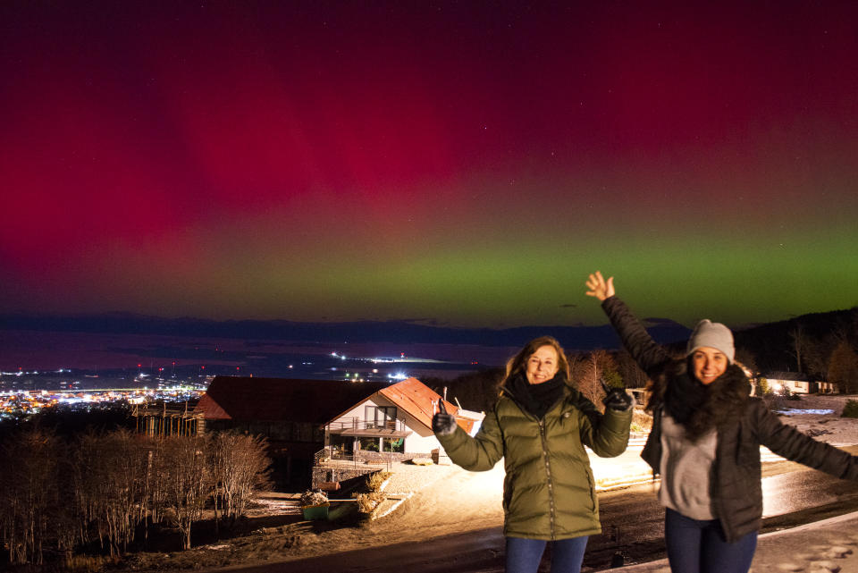 阿根廷火地島10日出現眩目南極光。Women pose for pictures as the Aurora Australis, also known as the Southern Lights, glow on the horizon as seen from Ushuaia, Tierra del Fuego, Argentina on May 10, 2024. The most powerful solar storm in more than two decades struck Earth, triggering spectacular celestial light shows from Tasmania to Britain -- and threatening possible disruptions to satellites and power grids as it persists into the weekend. (Photo by Alexis DELELISI / AFP) (Photo by ALEXIS DELELISI/AFP via Getty Images)