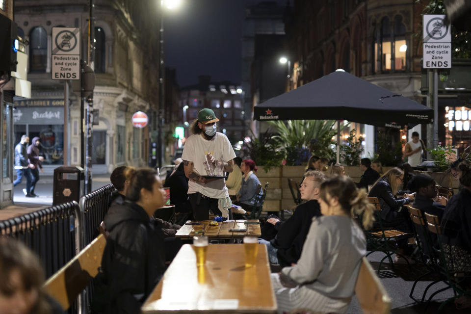 A member of bar staff wears a facemask at a bar in Manchester's Northern Quarter after Prime Minister Boris Johnson set out new restrictions to last "perhaps six months" to slow the renewed spread of coronavirus, Manchester, England, Tuesday Sept 22, 2020. The UK has reached "a perilous turning point", Boris Johnson said as he set out a raft of new coronavirus restrictions for England. ( AP Photo/Jon Super)