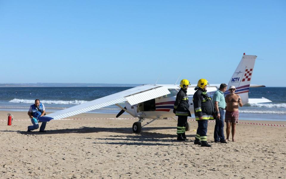 Emergency services inspect a plane that landed in an emergency on Sao Joao beach on Costa de Caparica in Almada, Portugal - Credit: EPA