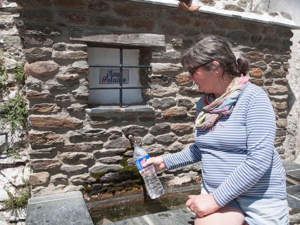 Woman filling plastic water bottle from natural spring in the High Alpujarras, Spain.