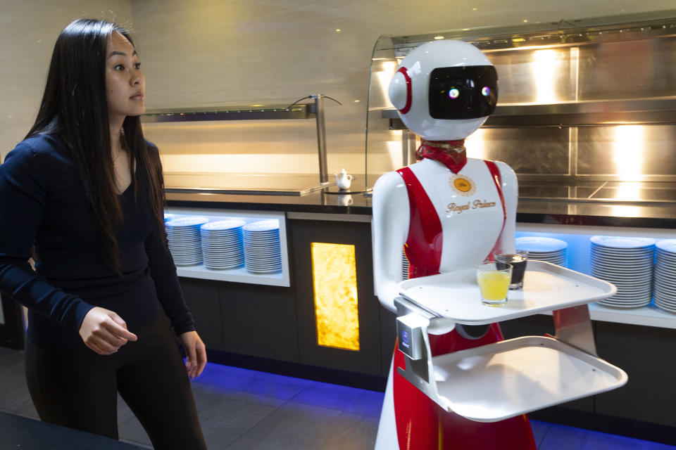 Leah Hu demonstrates the use of robots for serving purposes or for dirty dishes collection, as part of a tryout of measures to respect social distancing and help curb the spread of the COVID-19 coronavirus, at the family's Royal Palace restaurant in Renesse, south-western Netherlands, Wednesday, May 27, 2020. (AP Photo/Peter Dejong)