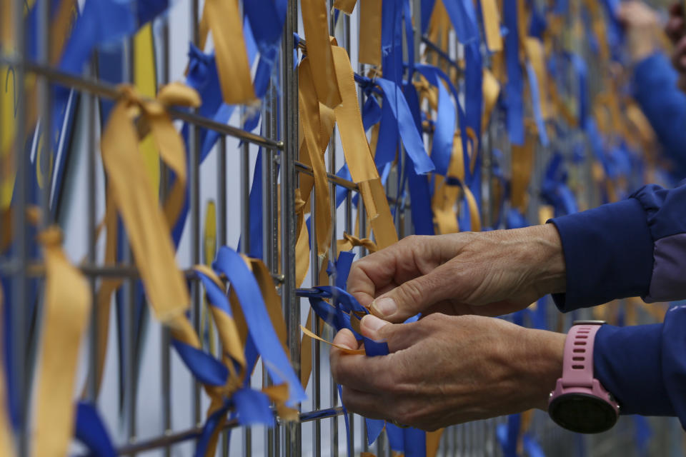 A person ties ribbons tp the "kindness wall" near the finish line of the Boston Marathon Saturday April 15, 2023, in Boston. (AP Photo/Reba Saldanha)