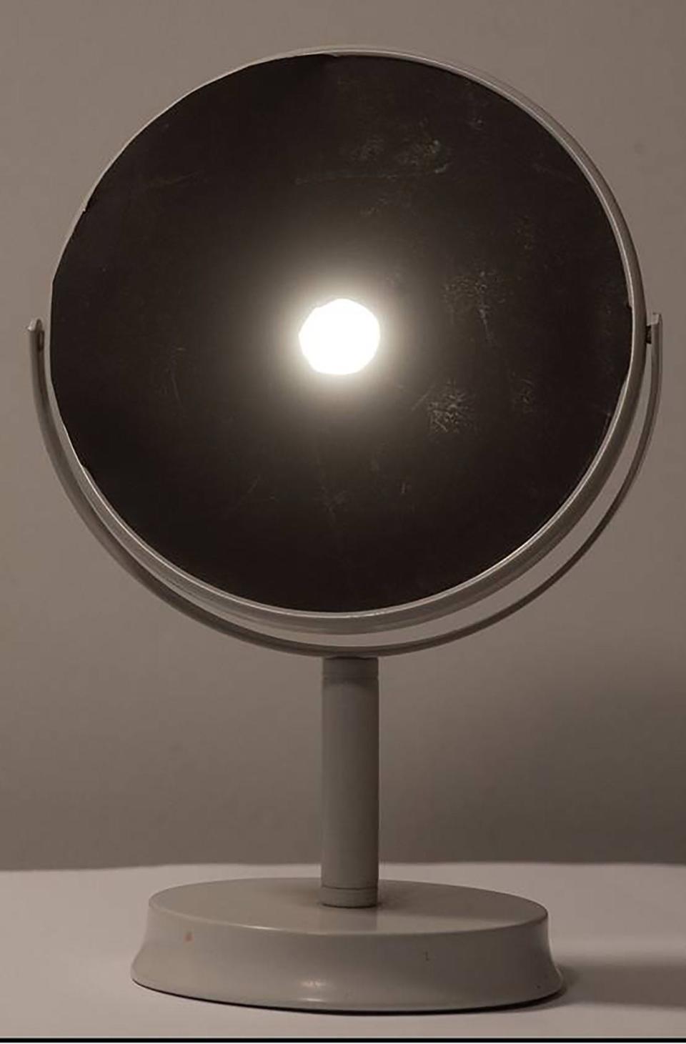 This simple "reflected pinhole" device can be easily made by covering a standard make-up mirror with black paper with a small hole. The reflected image of the eclipsed sun on to a light-colored surface allows safe viewing of the partially eclipsed sun.