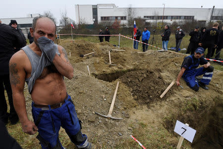 Gravediggers rest after competing in a grave digging championship in Trencin, Slovakia, November 10, 2016, where eleven pairs of gravediggers are competing in digging based on accuracy, speed, and aesthetic quality. REUTERS/Radovan Stoklasa