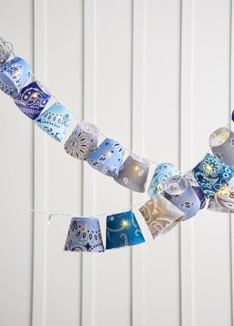 cups covered in blue bandanas in various shades are hung on string lights