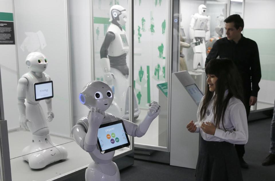 Charllotte Abbot reacts to the movement of Pepper an interactive French-Japanese robot, during a press preview for the Robots exhibition held at the Science Museum in London, Tuesday, Feb. 7, 2017. The exhibition which shows 500 years of mechanical and robotic advances is open to the public form Feb. 8 through to Sept. 3. (AP Photo/Alastair Grant)