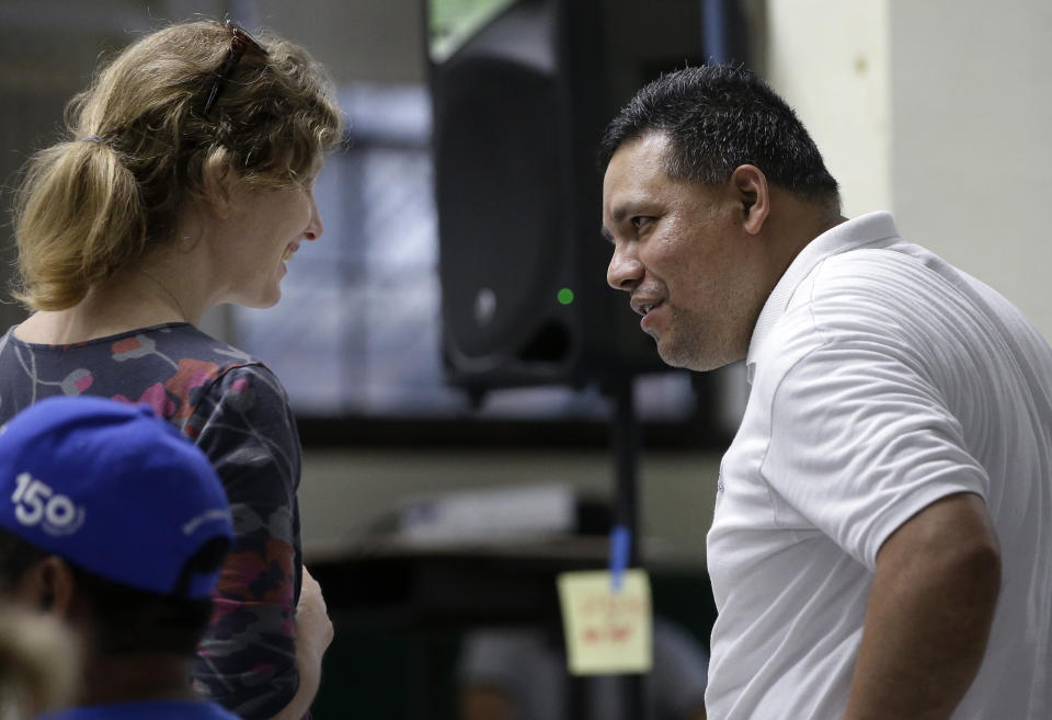 In this Sunday, June 30, 2019 photo Abby Taylor, left, chief of the civil rights division in the Massachusetts Attorney General's office, speaks with Jose Palma, right, head of the Massachusetts Temporary Protected Status (TPS) Committee, during a TPS meeting in Somerville, Mass. TPS is a program that offers temporary legal status to some immigrants in the U.S. who can't return to their country because of war or natural disasters. (AP Photo/Steven Senne)