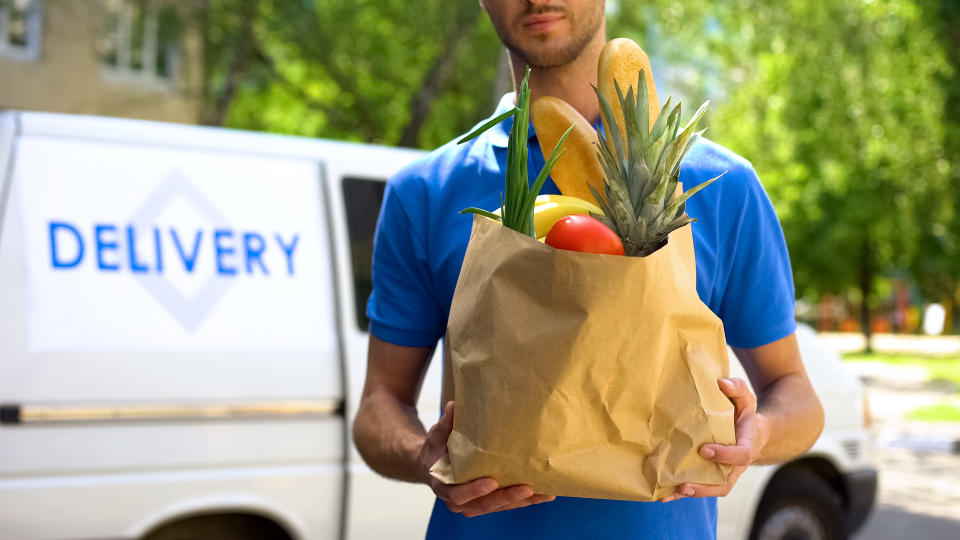 A delivery person brings groceries to a customer's door.