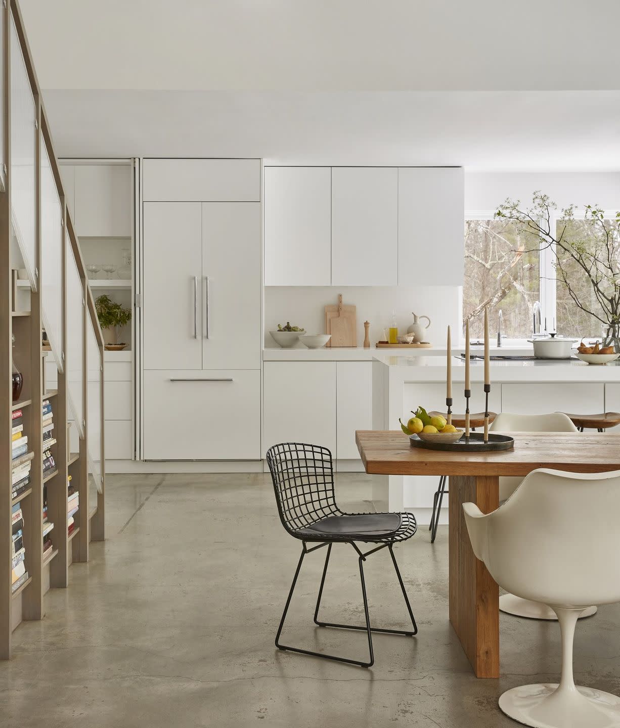 a kitchen with white cabinets and bookshelves under stairs