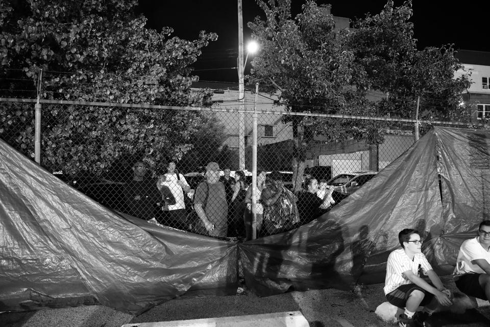 <p>People from the neighborhood watched through a spot where the blue tarp blocking the view had come loose, at the Brooklyn Smoker on Aug. 24, 2017. (Photo: Gordon Donovan/Yahoo News) </p>