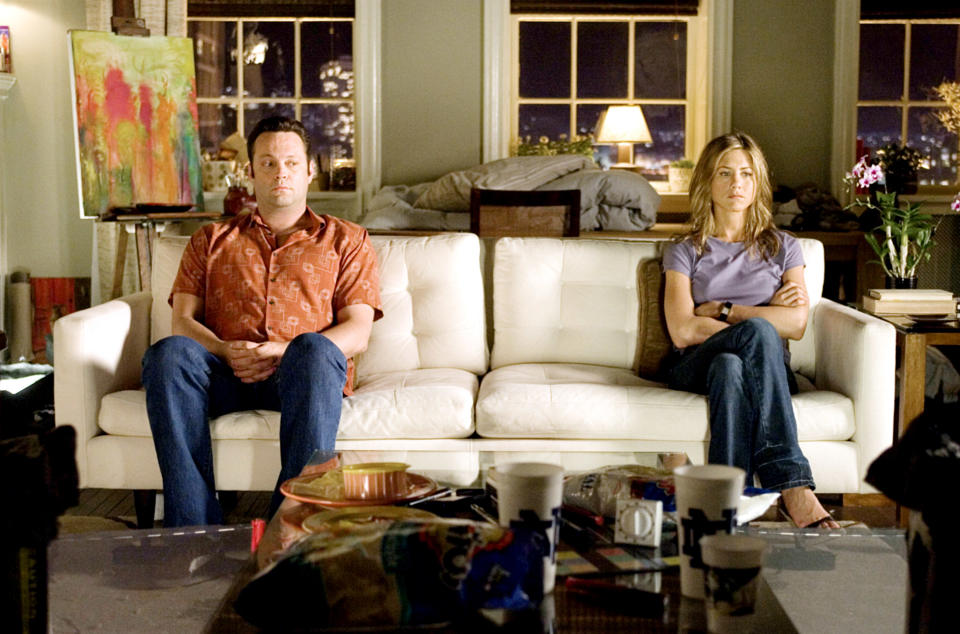 Jennifer Aniston and Vince Vaughn sit apart on a couch in a living room, facing forward with serious expressions, in a scene that suggests tension between them