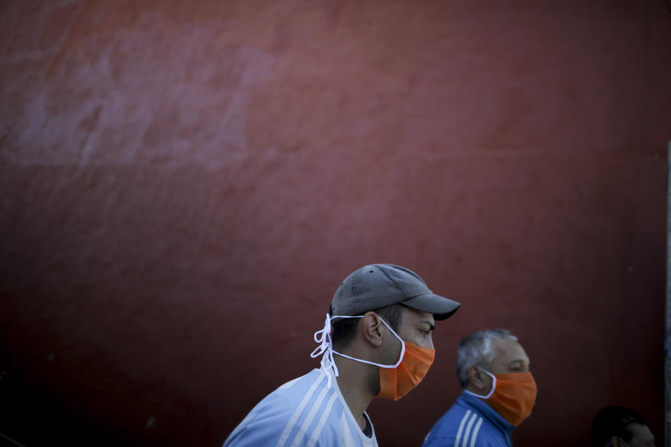 Volunteers at a soup kitchen sing the national anthem with soldiers who delivered the food on the outskirts of Buenos Aires, Argentina, Thursday, April 2, 2020, during a government-ordered lock down to contain the spread of the new coronavirus. (AP Photo/Natacha Pisarenko)