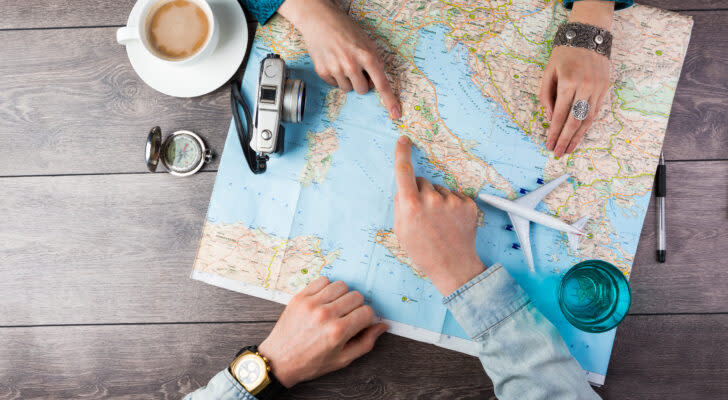 Top view of a couple pointing on a map as they plan for a vacation trip