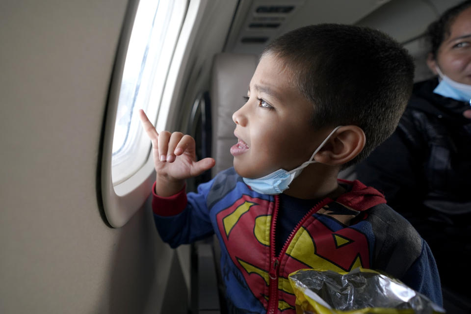 Yancarlos Amaya, 5, a migrant from Honduras, looks out an airplane window in Harlingen, Texas, as he and his mother, Celestina Ramirez, ride on an airplane to Houston, Wednesday, March 24, 2021. The mother and son, who were headed to Baltimore to reunite with Ramirez's brother, were permitted to stay in the U.S. after turning themselves into U.S. Customs and Border Protection upon crossing the border. (AP Photo/Julio Cortez)