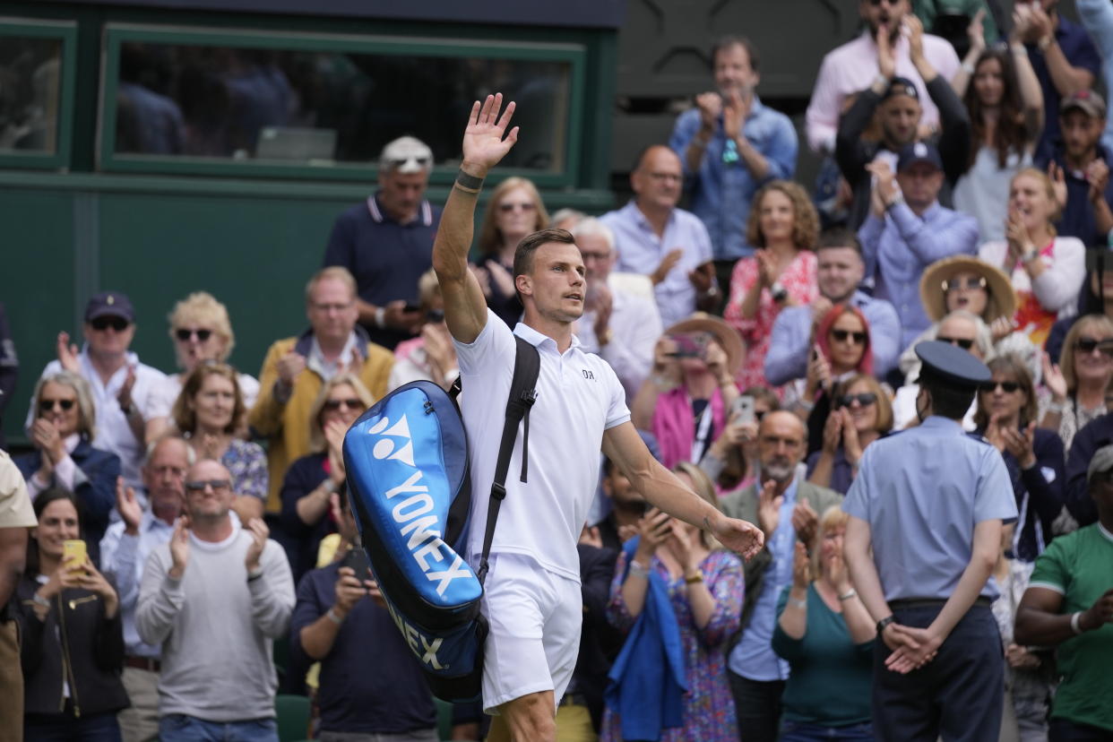 Hungary's Marton Fucsovics waves as he leaves the court after the men's singles quarterfinals match against Serbia's Novak Djokovic on day nine of the Wimbledon Tennis Championships in London, Wednesday, July 7, 2021.(AP Photo/Kirsty Wigglesworth)