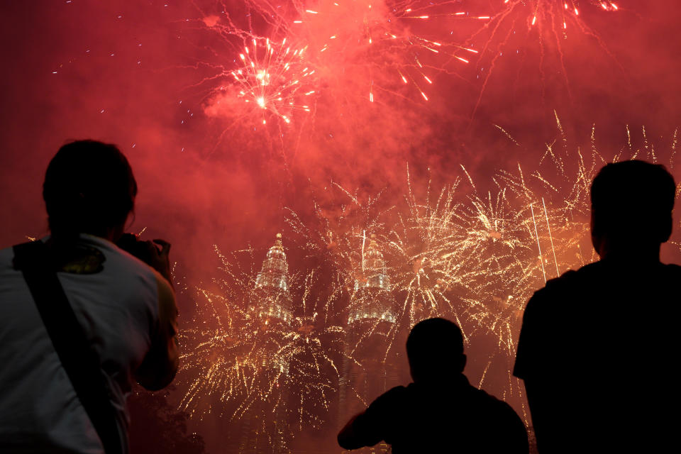 In this Tuesday, Jan. 1, 2019, file photo, spectators watch as fireworks explode in front of Malaysia's landmark building, the Petronas Twin Towers, during the New Year's celebration in Kuala Lumpur, Malaysia. (AP Photo/Yam G-Jun, File)