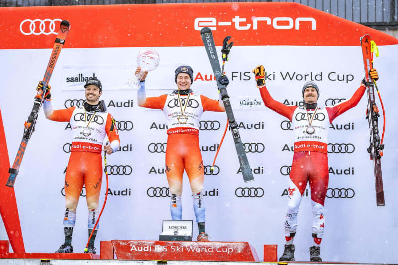 (L-R) Swiss ski racer second placed Loic Meillard, Swiss Alpine Skiing Overall World Cup winner Marco Odermatt and Austrian third placed Manuel Feller celebrate at the award ceremony of the Men's Overall downhill World Cup. Johann Groder/APA/dpa