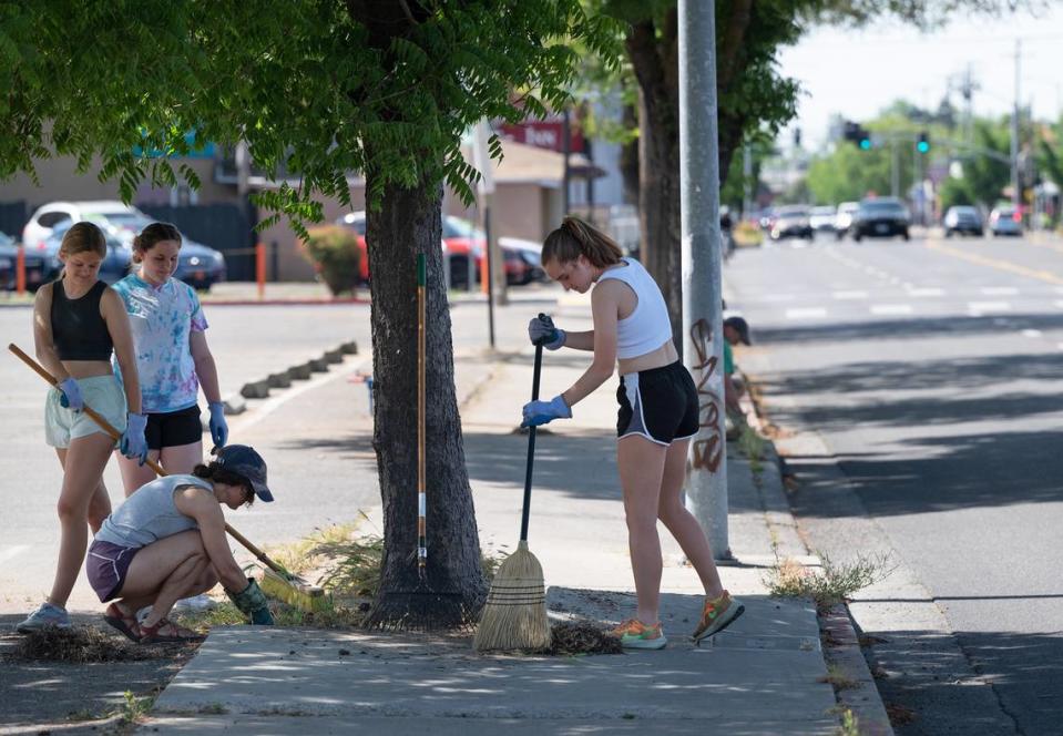 Amy Leach, kneeling, weeds along McHenry Avenue with her two daughters Zoe, 15, right, Edie, 13, left, and friend Grace Huffman during Love Modesto community service day in Modesto, Calif., Saturday, April 29, 2023.