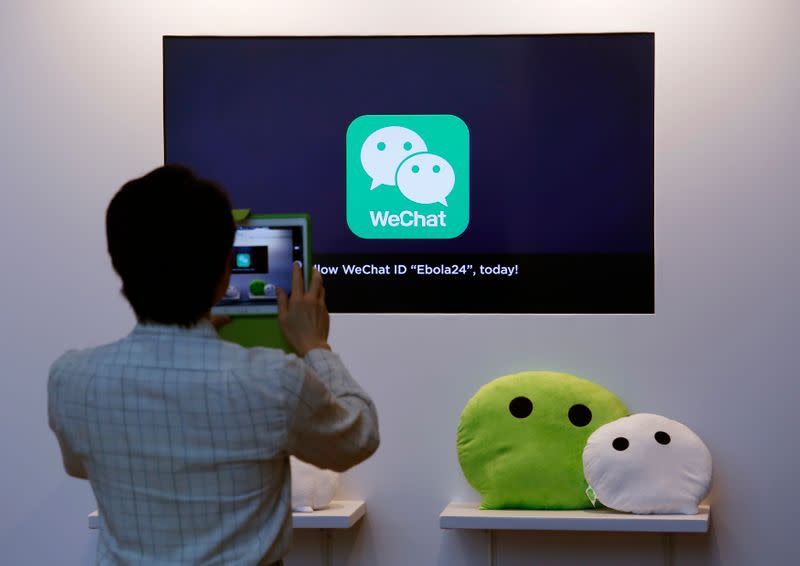 A man takes a photograph of a counter promoting WeChat displayed at a news conference in Hong Kong