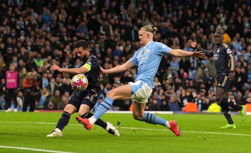 Manchester City's Erling Haaland (C) and Real Madrid's Fernandez Nacho battle for the ball during the UEFA Champions League quarter-final second leg soccer match between Manchester City and Real Madrid at the Etihad Stadium, Manchester. Martin Rickett/PA Wire/dpa