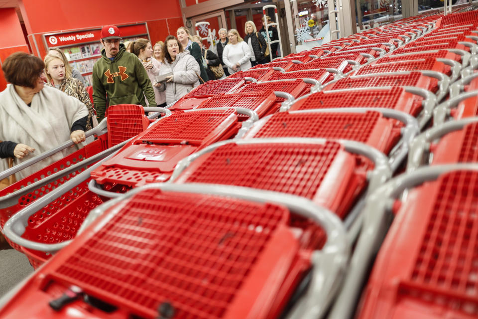 FILE- In this Friday, Nov. 23, 2018, file photo, shoppers enter and take their shopping carts during a Black Friday sale at a Target store in Newport, Ky. On Tuesday, Nov. 27, the Conference Board releases its November index on U.S. consumer confidence. (AP Photo/John Minchillo, File)