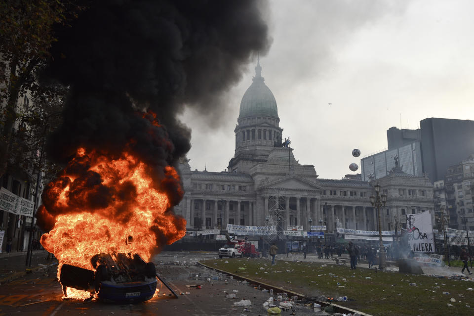 Un automóvil arde durante enfrentamientos entre la policía y manifestantes antigubernamentales frente al Congreso, donde los senadores debaten proyectos de ley promovidos por el presidente argentino Javier Milei en Buenos Aires, Argentina, el miércoles 12 de junio de 2024. (AP Foto/Gustavo Garello)