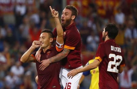 AS Roma's Francesco Totti (L) celebrates with his teammates Daniele De Rossi (top) and Mattia Destro after scoring a penalty against Chievo Verona during their Italian Serie A soccer match at the Olympic stadium in Rome October 18, 2014. REUTERS/Tony Gentile