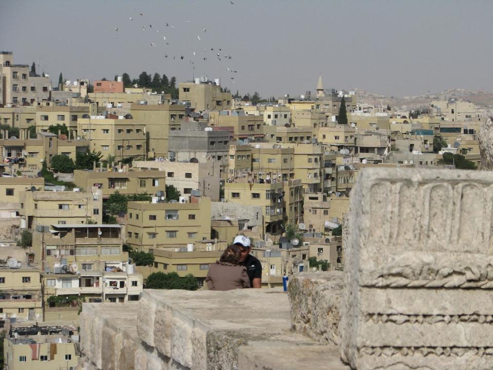 This April 21, 2016 photo shows two young people talking among the ancient ruins of Amman's Citadel hill, the historical core of Jordan's capital which is seen sprawling behind them. This Middle Eastern country delivers a blockbuster list of iconic ancient monuments, otherworldly landscapes and warmhearted hospitality, with Petra as its tourism jewel. (Giovanna Dell'Orto via AP)