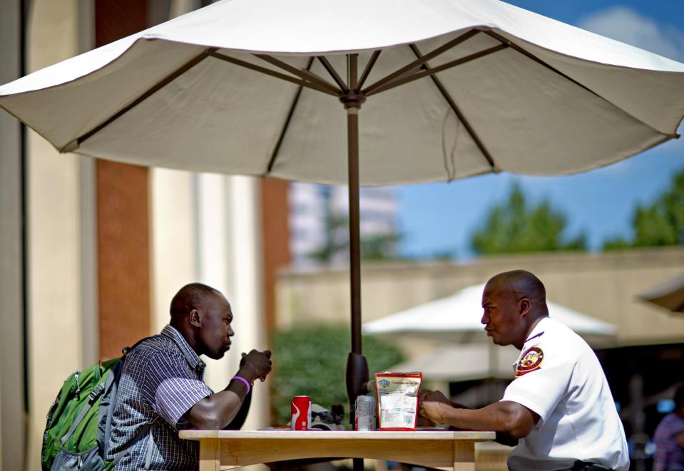 In this Friday, Sept. 20, 2013 photo, airport chaplains Romano Nereo, left, of Juba International Airport in South Sudan, and Lt. Norman Miller, of the Atlanta Fire Department, sit for lunch during the International Association of Civil Aviation Chaplains' annual conference, in Atlanta. Airports are mini-cities with their own movie theaters, fire departments and shopping malls. Many also have chapels, which are staffed by a mix of 350 part- and full-time chaplains worldwide who are Catholic, Protestant and, to a lesser extent, Jewish, Muslim or Sikh. (AP Photo/David Goldman)