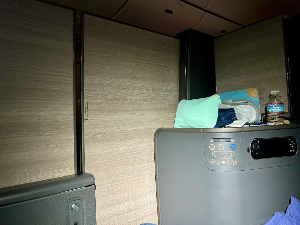 The author's enclosed business class seat with a blue bag on the side table.