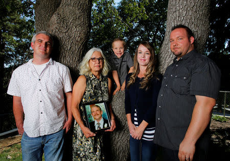 Nancy Schrock holds a picture of her late husband Thomas as she poses for a photograph between her son Matthew (L) grandson Caleb, daughter Sarah Palmer, and son-in-law Chris, while at her home in Oak Glen, California July 26, 2016. REUTERS/Mike Blake/Files