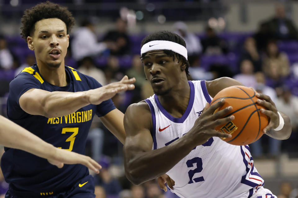 FILE - West Virginia's Tre Mitchell (3) defends as TCU forward Emanuel Miller (2) works to the basket for a shot in the first half of an NCAA college basketball game, Tuesday, Jan. 31, 2023, in Fort Worth, Texas. Miller went through the draft process before deciding to return for his senior season at TCU, where his coach wants him to shoot more 3-pointers as the Horned Frogs try to get to their third NCAA Tournament in a row. (AP Photo/Ron Jenkins, File)