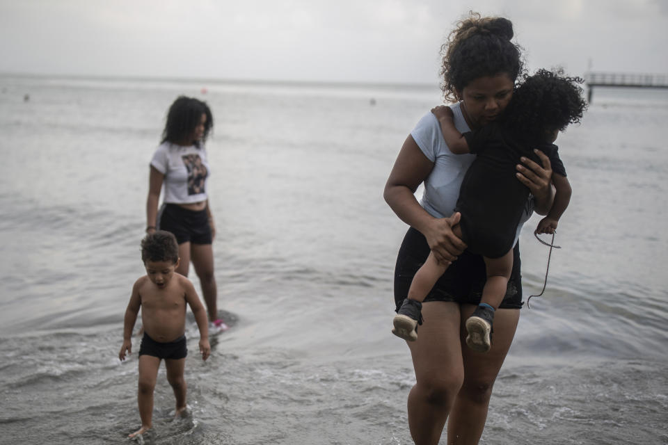 A family of Venezuelan migrants bathe in the beach in Necocli, Colombia, Sunday, May 7, 2023. Necocli is a route for migrants looking to board boats to cross the Uraba Gulf on their way to start the walk across the Darien Gap to Panama. (AP Photo/Ivan Valencia)