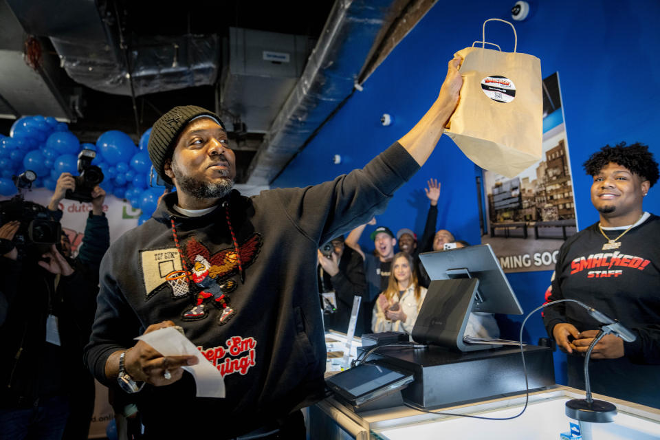 Roland Conner, left, holds the first legal purchase of cannabis, bought from his son Darius, right, from their "pop up" dispensary location of their business Smacked , Tuesday, Jan. 24, 2023, in New York. The store is the first Conditional Adult-Use Retail Dispensary (CAURD) opening since the legalization of cannabis that is run by businesspeople who had been criminalized by cannabis prohibition. (AP Photo/John Minchillo)