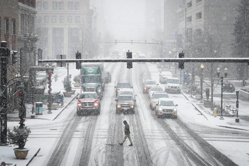 A man crosses a snow covered West Main Street as the Thursday, Jan. 6 snow began to accumulate in downtown Lexington.