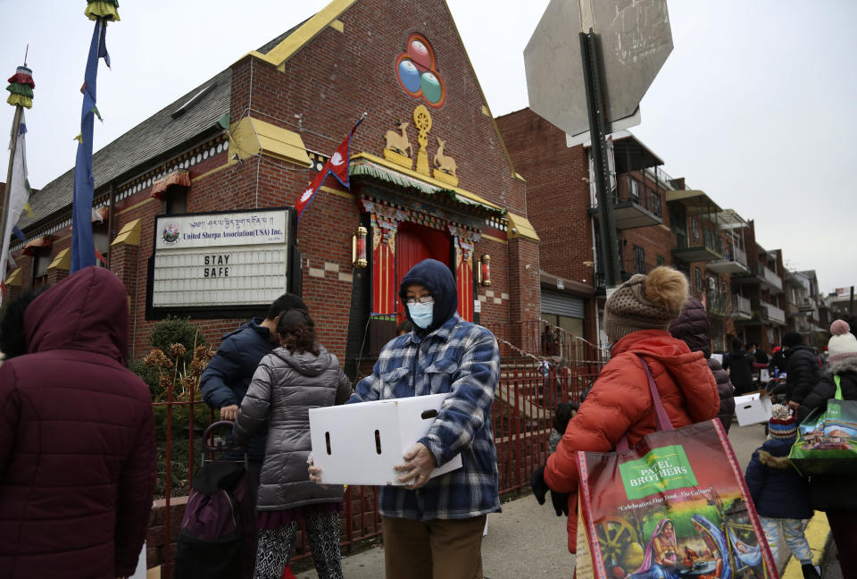 People receive free food from the United Sherpa Association's weekly food pantry on Friday, Jan. 15, 2021, in the Queens borough of New York. The pantry began in April with a focus on the Nepalese community, international students and families living in the country without permission. (AP Photo/Jessie Wardarski)