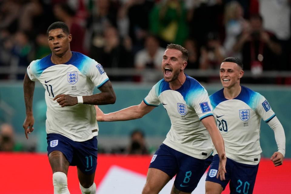 Marcus Rashford celebrates with teammates  Jordan Henderson and Phil Foden after scoring the opening goal during the World Cup group B soccer match between England and Wales. (AP)