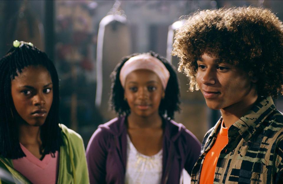 Corbin Bleu smiling while standing next to two girls